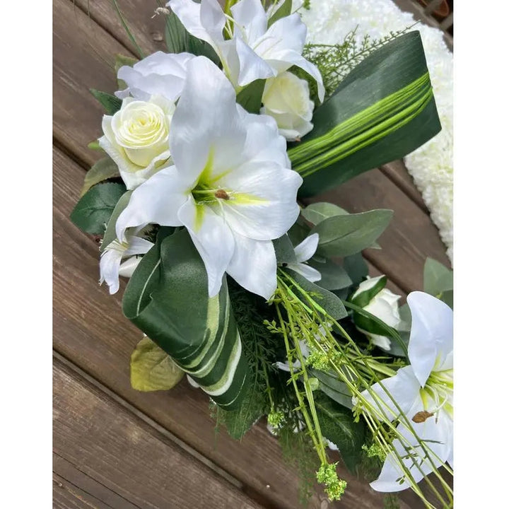A pair of hands gently placing a small, handwritten sympathy card next to a bouquet of light pink roses and baby's breath.