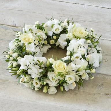 Traditional white lily and carnation casket spray arrangement, close up, soft daylight, respectful setting.